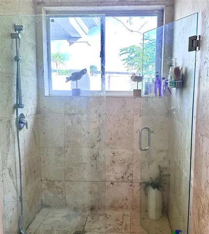 a bathroom with a granite countertop shower a sink and a window