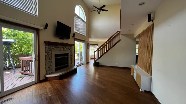 a view of a livingroom with furniture a fireplace wooden floor and windows
