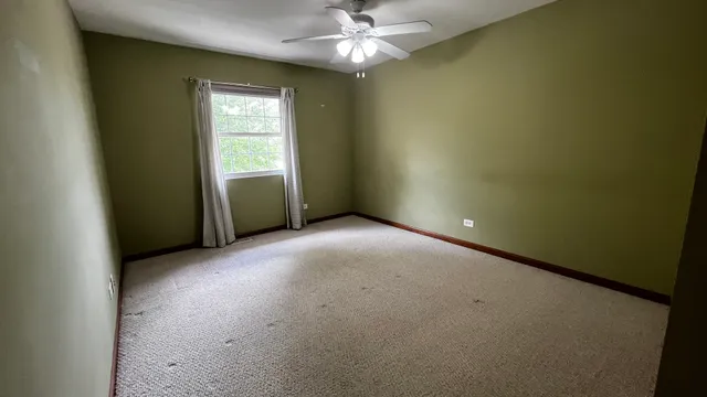 an empty room with a window and a fan