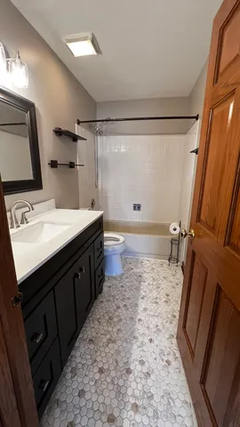 a bathroom with a sink a toilet a mirror and shower