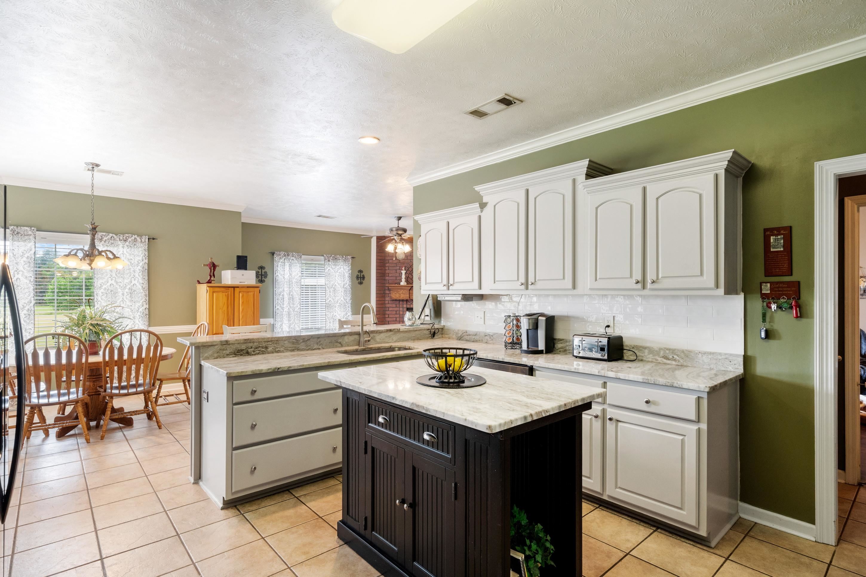 7757 Brunswick Road Millington, TN 38053 - Photo 5 of 40 Kitchen featuring light-toned cabinetry, light granite countertops, a dark wood-finish island, and tile flooring