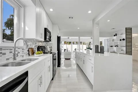 a large kitchen with stainless steel appliances lots of white cabinets and wooden floors