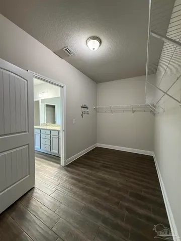 an empty room with wooden floor and a kitchen