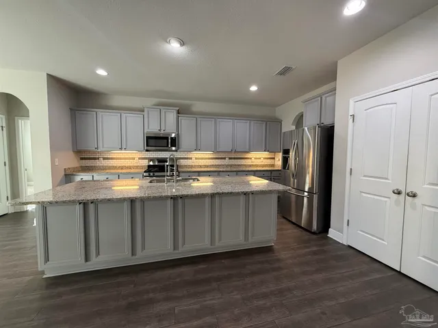 a kitchen with stainless steel appliances granite countertop a refrigerator a stove a sink and a microwave