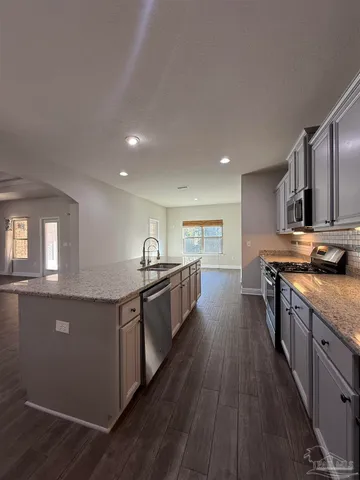 a large kitchen with stainless steel appliances a sink a stove top oven a counter space and cabinets