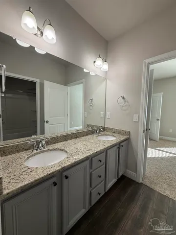 a bathroom with a granite countertop double vanity sink and a mirror