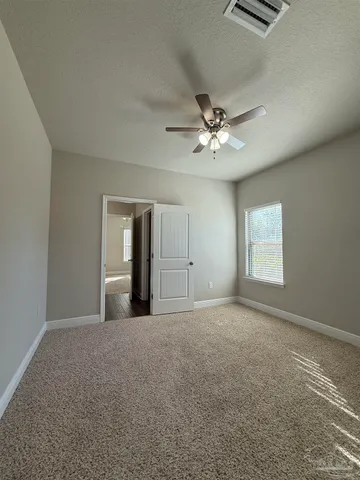 an empty room with chandelier fan and windows