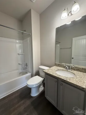 a bathroom with a granite countertop sink a toilet a mirror and bathtub