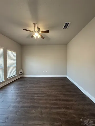a view of an empty room with window and wooden floor