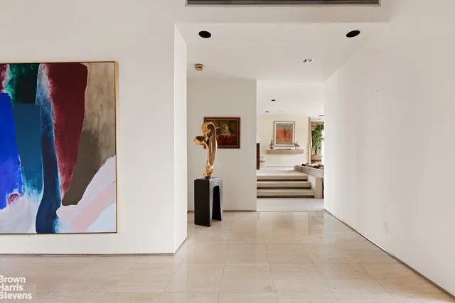 a view of a hallway with wooden floor and a living room