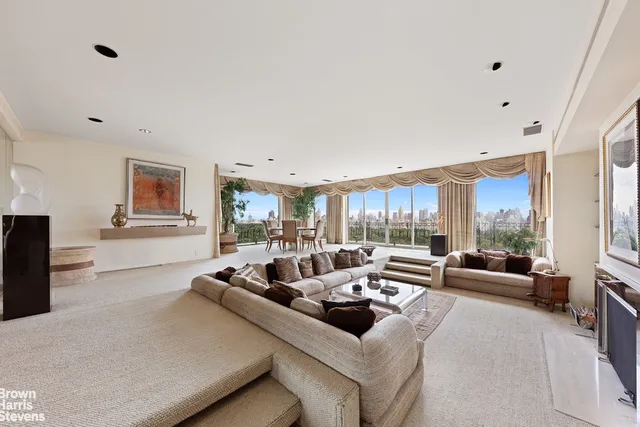 a living room with furniture large windows and wooden floor