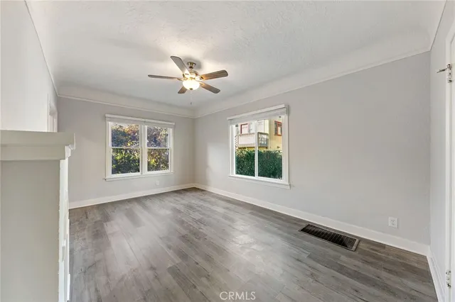 a view of an empty room with a window and wooden floor