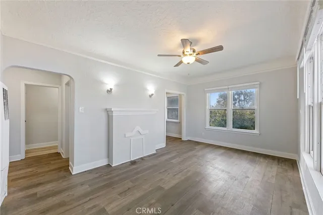 a view of an empty room with a window and wooden floor