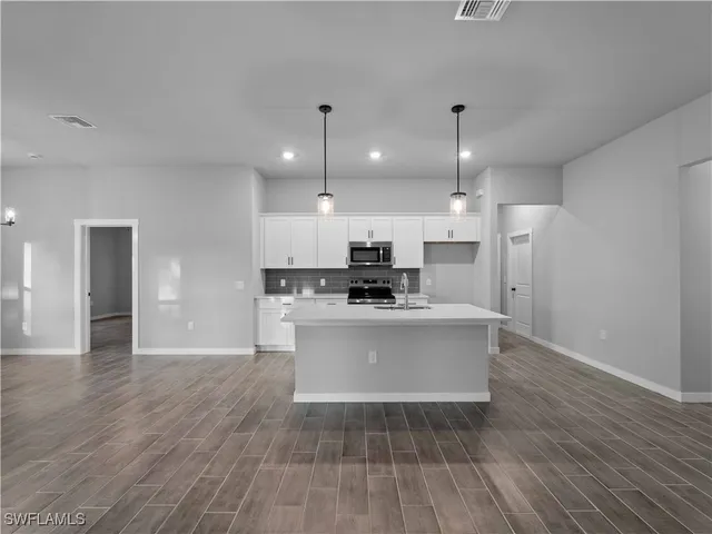 a view of an empty room with chandelier fan and fire place