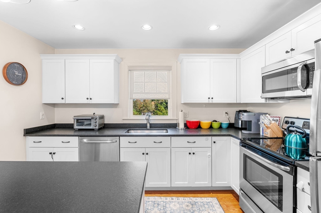 2-4 Gracie Lane, Unit 4 Swampscott, MA 01907 - Photo 13 of 37 a kitchen with granite countertop a stove a sink dishwasher and white cabinets with wooden floor
