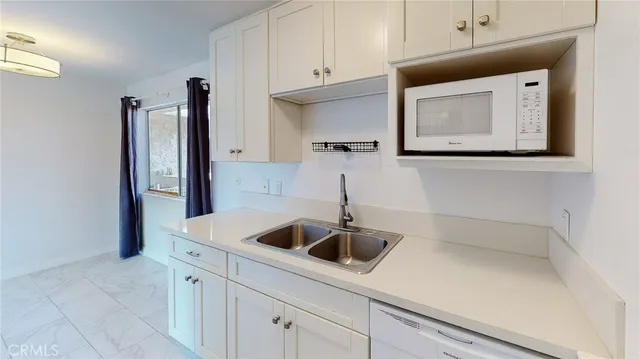a kitchen with white cabinets and white appliances