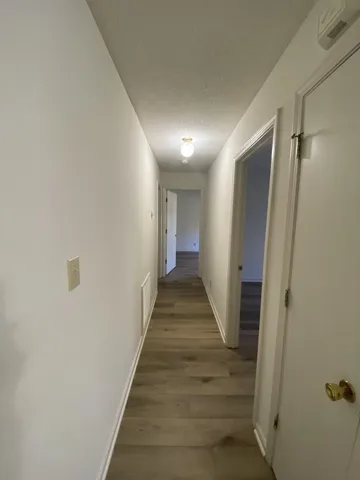 a view of a hallway with wooden floor and staircase
