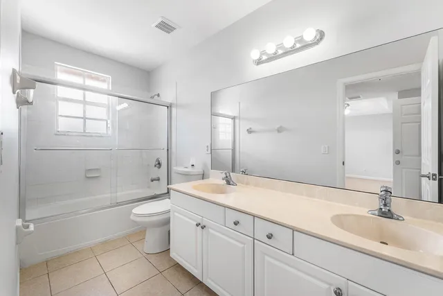 a bathroom with a double vanity sink toilet mirror and shower