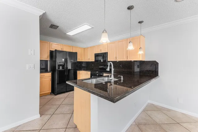 a kitchen with stainless steel appliances granite countertop a sink a refrigerator and a counter top space
