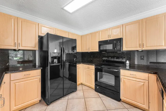 a kitchen with granite countertop a stove a sink and a refrigerator