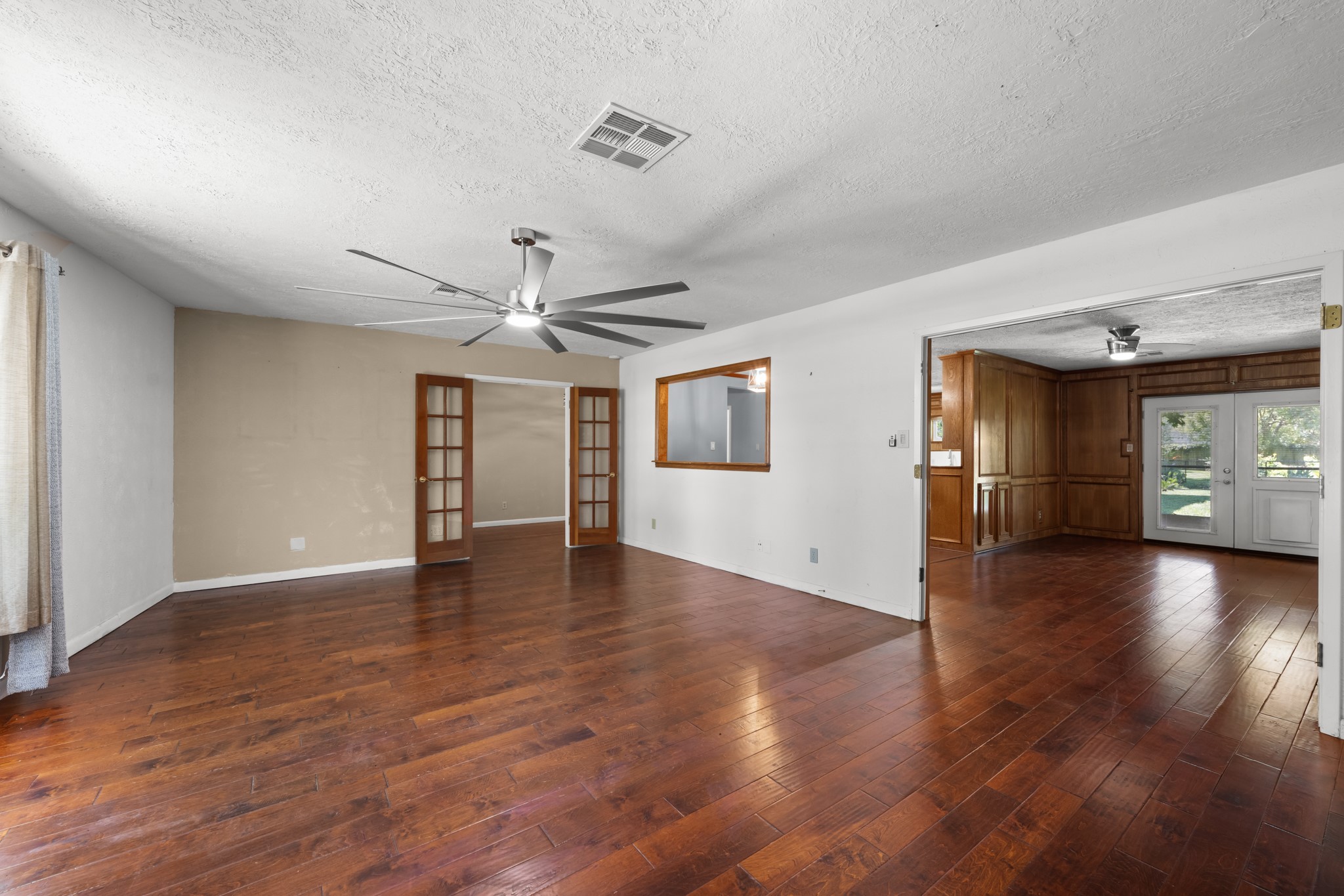 616 Cannan Drive Angleton, TX 77515 - Photo 6 of 49 Generous in size and filled with flexibility, this living area features rich wood-look flooring, abundant wall space for furnishings, and a modern ceiling fan. French doors provide an elegant transition to adjoining spaces, while the open connection to the kitchen enhances the home's comfortable flow for gatherings and everyday living.