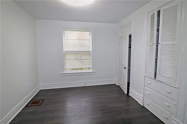 an empty room with wooden floor and window