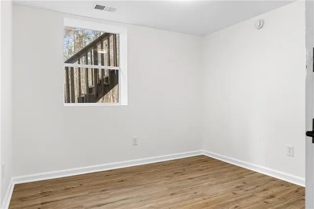 a view of an empty room with wooden floor and a window