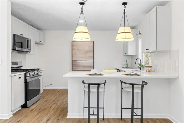a kitchen with stainless steel appliances granite countertop a sink a stove and a wooden floor