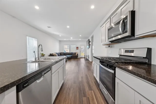 a kitchen with stainless steel appliances granite countertop a stove a sink and a microwave