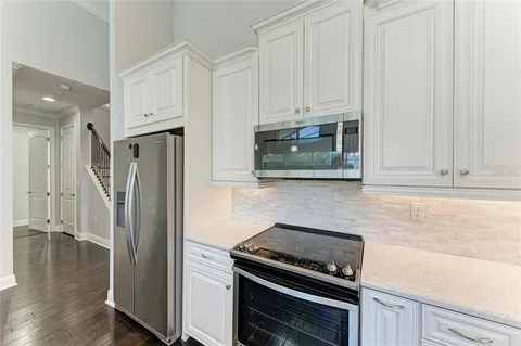 a kitchen with stainless steel appliances a refrigerator a stove and white cabinets