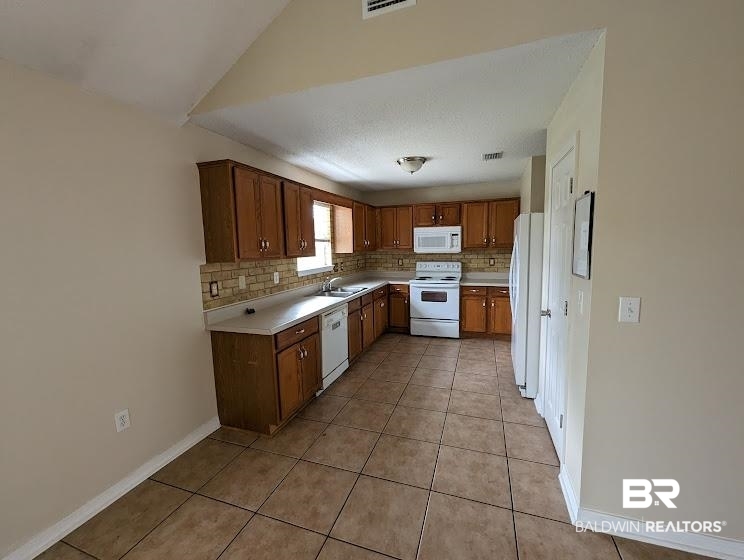 12971 Labradors Run Foley, AL 36535 - Photo 5 of 23 Spacious kitchen with a vaulted ceiling, wood-finish cabinetry, tile flooring, and a brick-patterned backsplash