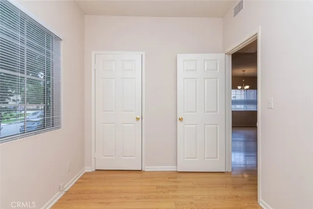 a view of an empty room with wooden floor and closet