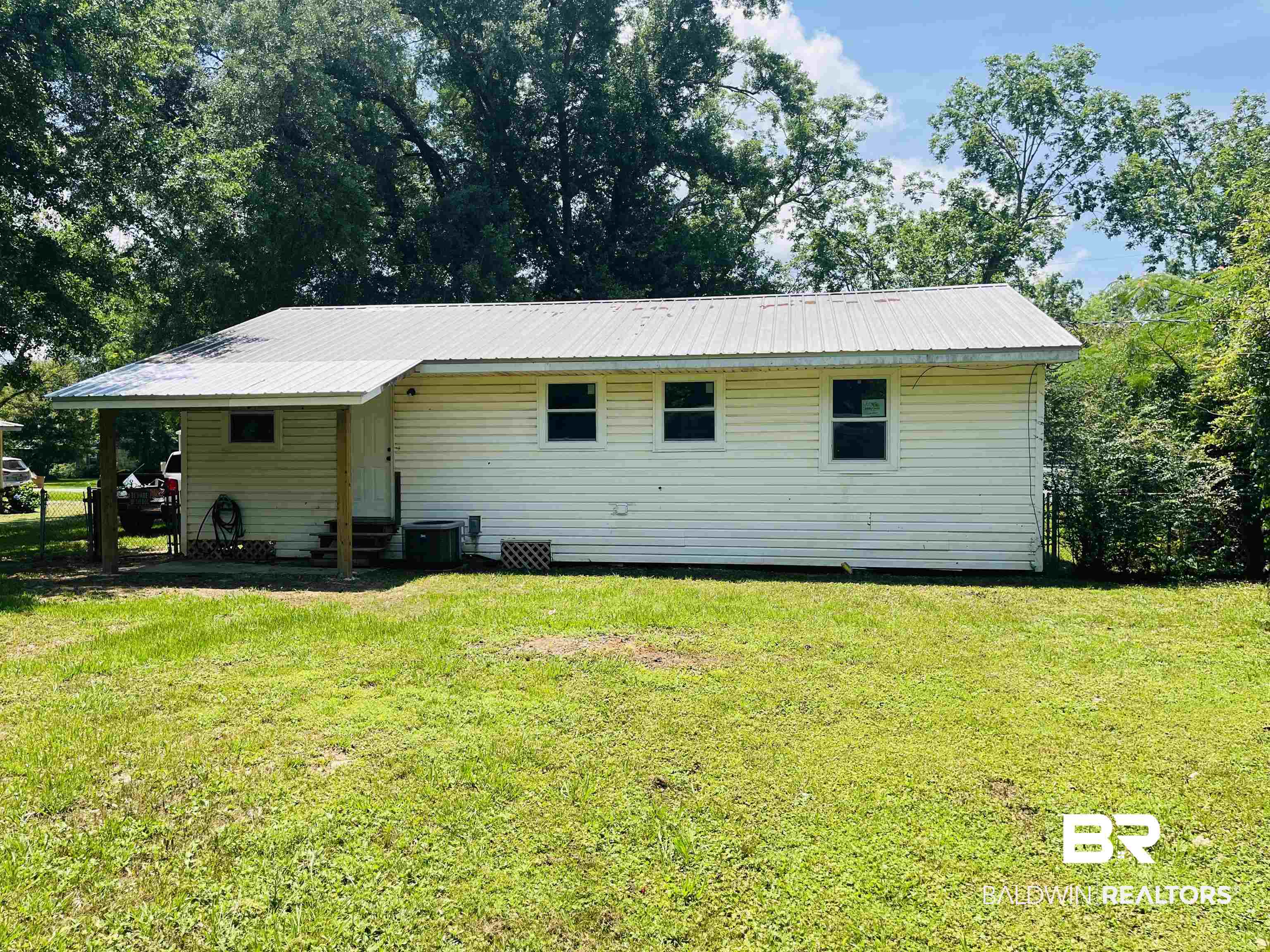 18855 Crocker Lane Foley, AL 36535 - Photo 20 of 25 Back of property with metal roof, a lawn, a carport, and central AC unit