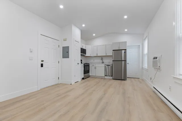 a view of kitchen with refrigerator cabinets and wooden floor