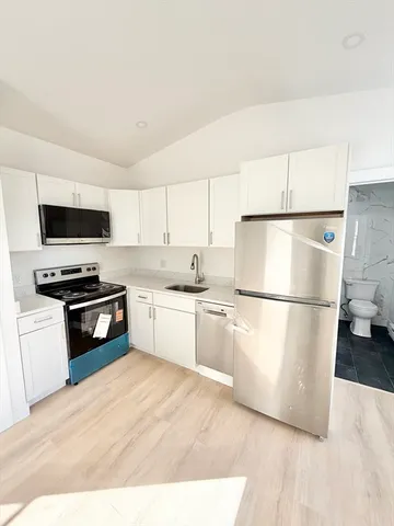 a kitchen with a refrigerator a microwave a stove and white cabinets