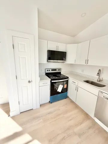 a kitchen with a sink and a stove top oven with white cabinets