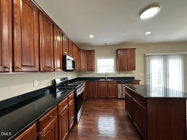 a kitchen with stainless steel appliances granite countertop wooden cabinets a stove top oven a sink and dishwasher