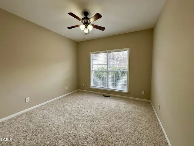 an empty room with a chandelier fan and windows