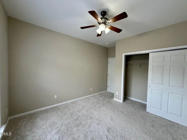 an empty room with closet and a chandelier fan