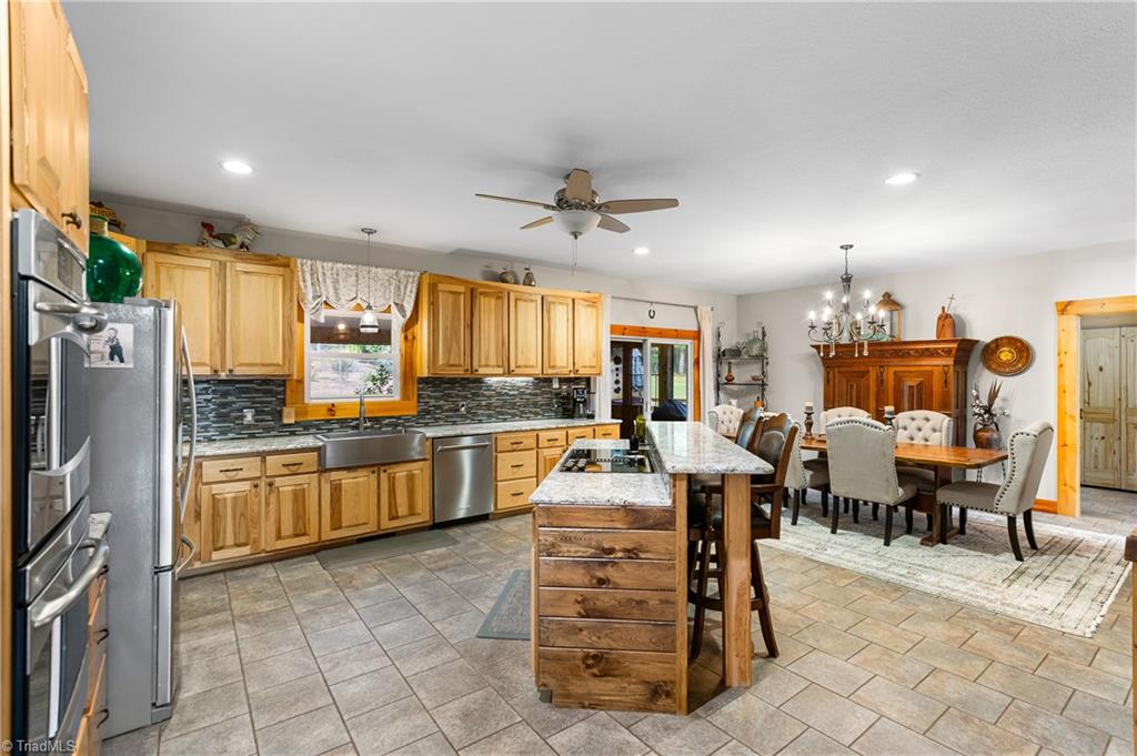 246 Bear Trail Lowgap, NC 27024 - Photo 12 of 50 Large open kitchen with custom hickory cabinets, island with seating, granite counter tops and stainless steel appliances. Dining area to the right. Sliding doors in the back to the screened-in back porch.