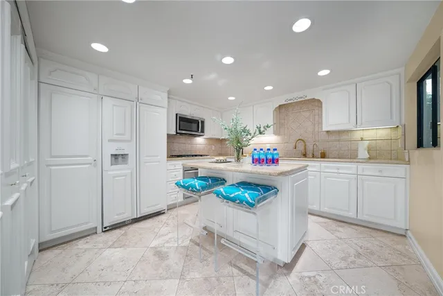 a kitchen with granite countertop a refrigerator and white cabinets