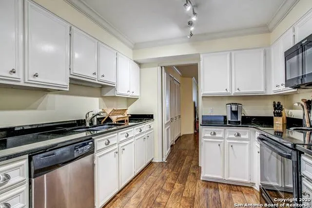 a kitchen with granite countertop a sink a stove and cabinets