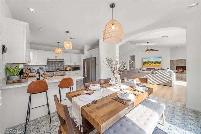 a kitchen with stainless steel appliances kitchen island granite countertop a stove a sink a dining table and chairs with wooden floor