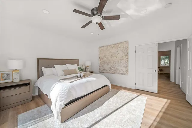 a bedroom with a bed ceiling fan and a wooden floor