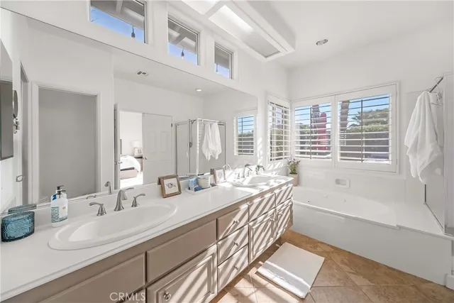 a bathroom with double vanity sinks a large mirror and a bathtub