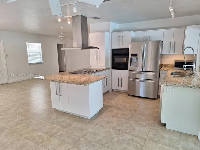 a kitchen with stainless steel appliances granite countertop a refrigerator a stove a sink and a refrigerator