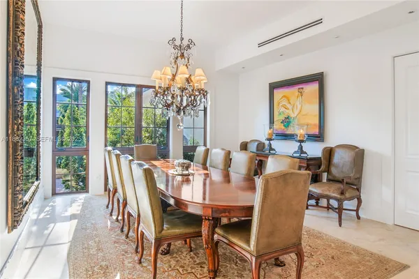 a view of a dining room with furniture a chandelier and large windows
