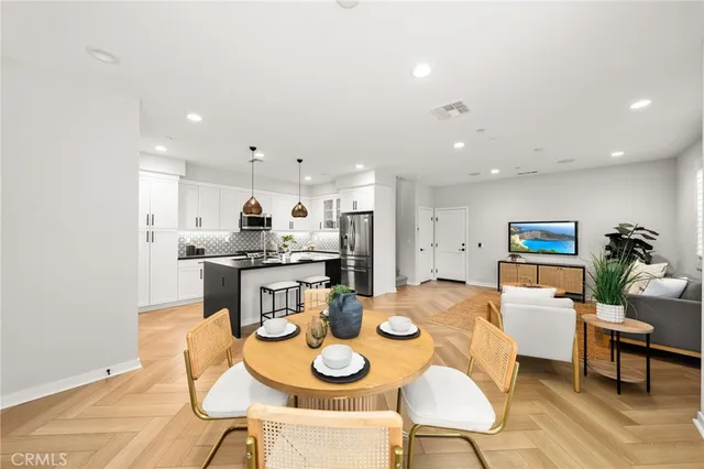 a kitchen with stainless steel appliances kitchen island granite countertop a dining table and chairs with wooden floor