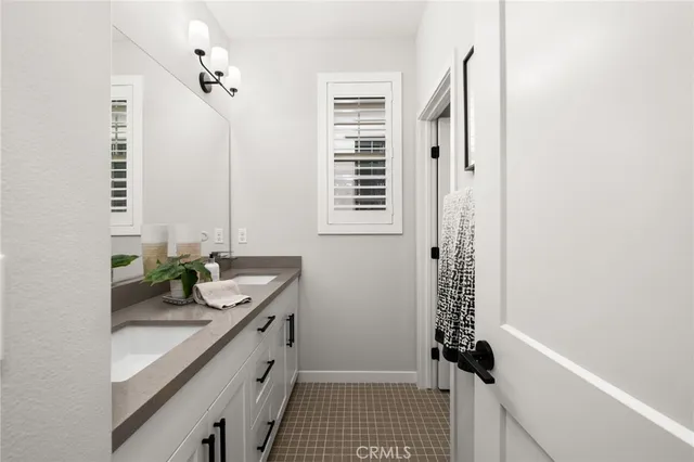 a bathroom with a sink a granite countertop window and a shower