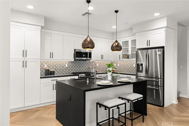 a kitchen with stainless steel appliances granite countertop a sink a stove a refrigerator and island with wooden floor